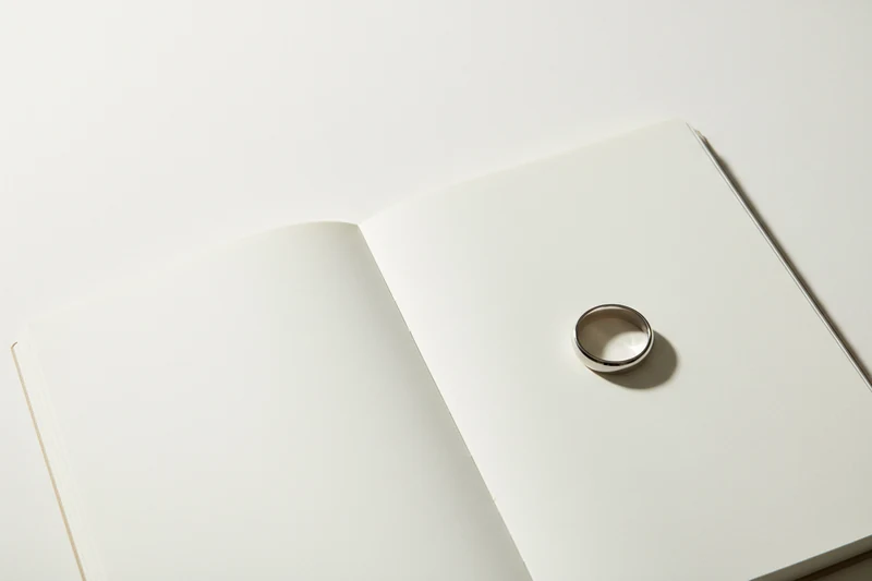 A platinum ring resting on an open blank notebook page.